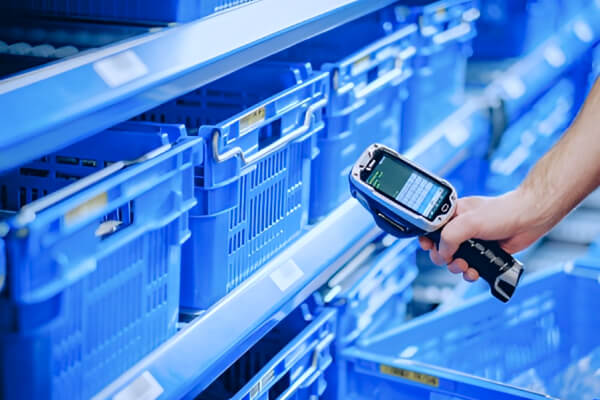 Eine Person scannt Produkte mit einem Handscanner in einem Warenlager.