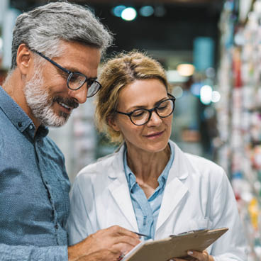 Apotheken-Sortiment digital steuern Ein Mann und eine Frau stehen in einer Apotheke und schauen auf ein Tablet.
