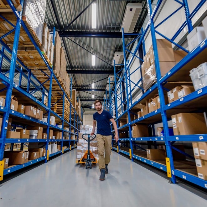 Production worker walking down aisle in Abacus Medicine's warehouse in the Netherlands